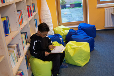 Foto Schulbibliothek, Junge blättert in Buch.